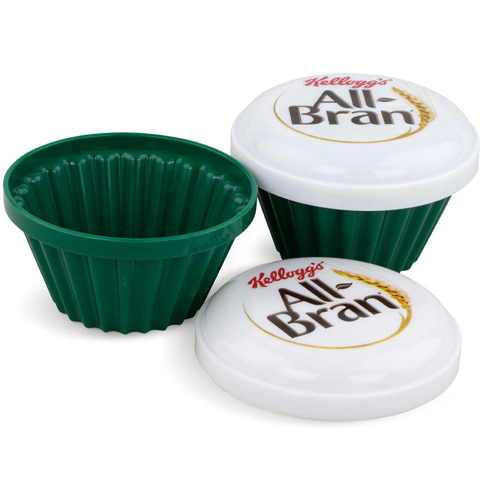 Two green Kellogg's All-Bran® microwave muffin cups with white branded lids, displayed open and closed.